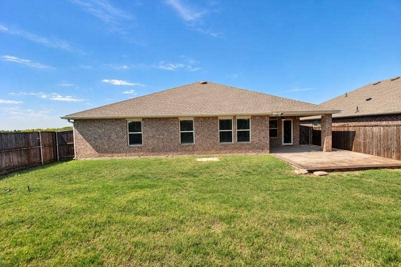 339 Exploration Way, Fate, TX 75189 Expansive backyard with a manicured lawn, full brick exterior, covered patio, and wood privacy fencing
