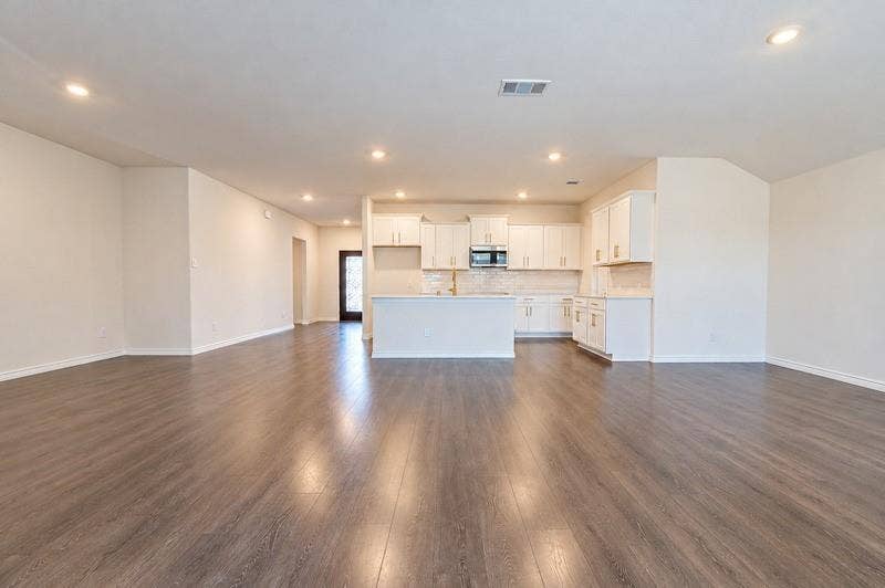 339 Exploration Way, Fate, TX 75189 Open-concept living space featuring wood-finish flooring, recessed lighting, and a kitchen with white cabinetry, a central island, and a tile backsplash