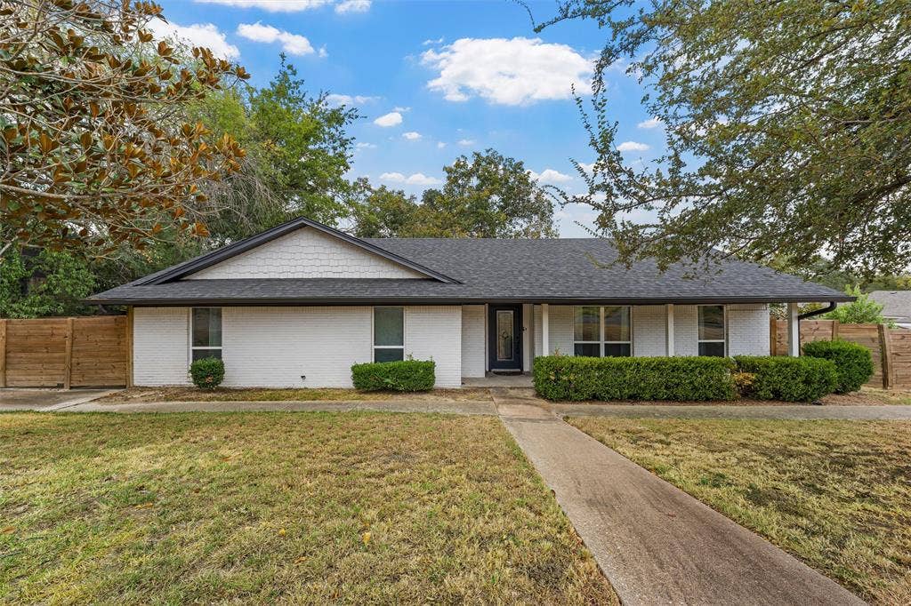 1132 Western Oaks Drive, Woodway, TX 76712 White brick exterior with a dark shingle roof, featuring a gabled entryway and a dark-framed front door