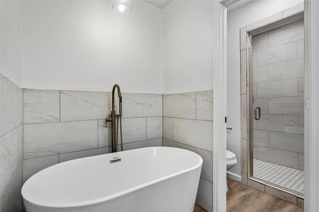 1132 Western Oaks Drive, Woodway, TX 76712 Freestanding soaking tub with floor-mounted fixture, tiled wainscoting, and recessed ceiling lighting