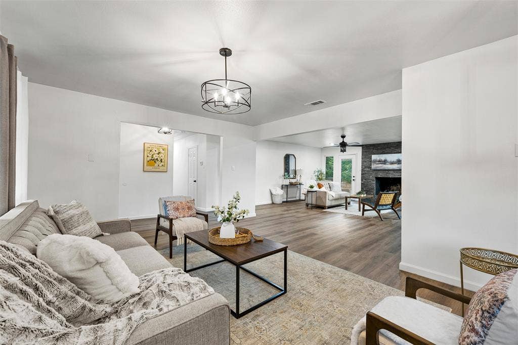 1132 Western Oaks Drive, Woodway, TX 76712 Expansive living area featuring wood-finish flooring, a contemporary ceiling light fixture, and a stone-clad fireplace
