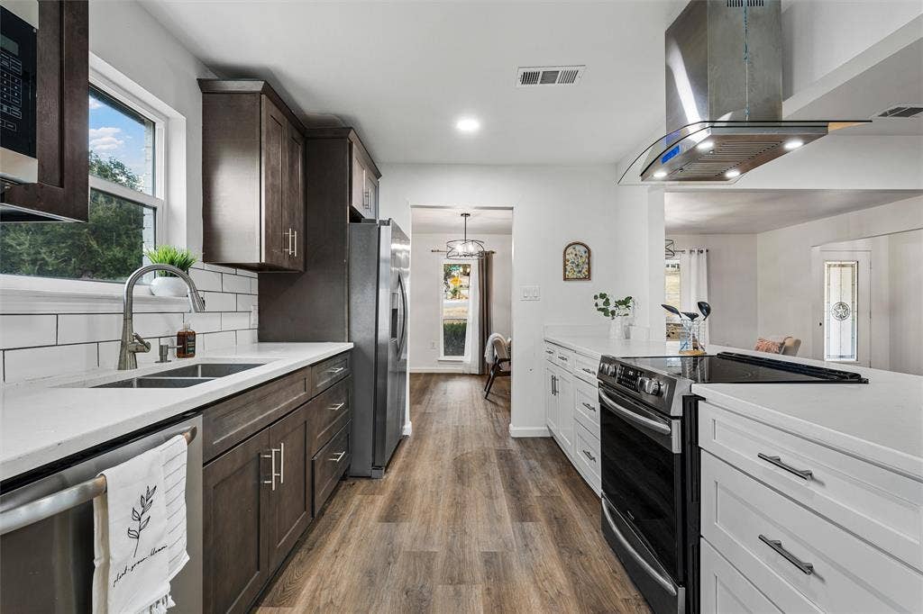 1132 Western Oaks Drive, Woodway, TX 76712 Modern kitchen featuring wood-finish flooring, white countertops, two-tone cabinetry, a stainless steel sink, and a built-in electric range with an overhead vent hood