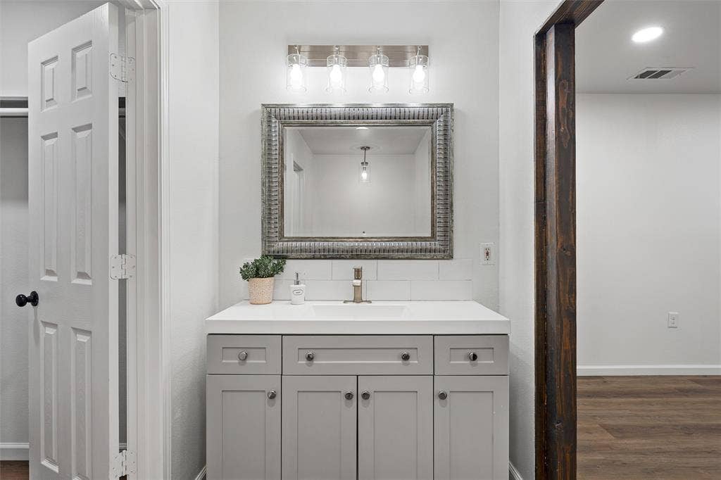 1132 Western Oaks Drive, Woodway, TX 76712 Vanity with light gray shaker-style cabinetry, white countertop, and subway tile backsplash