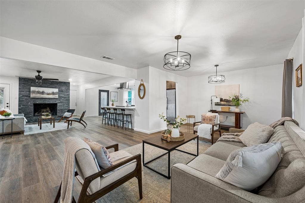 1132 Western Oaks Drive, Woodway, TX 76712 Spacious living area featuring wood-finish flooring, a stacked stone fireplace, and contemporary lighting fixtures