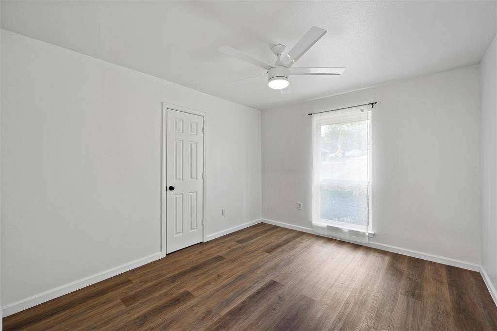 1132 Western Oaks Drive, Woodway, TX 76712 Wood-finish flooring, white paneled door, modern ceiling fan with integrated lighting, and a single window with curtain rod