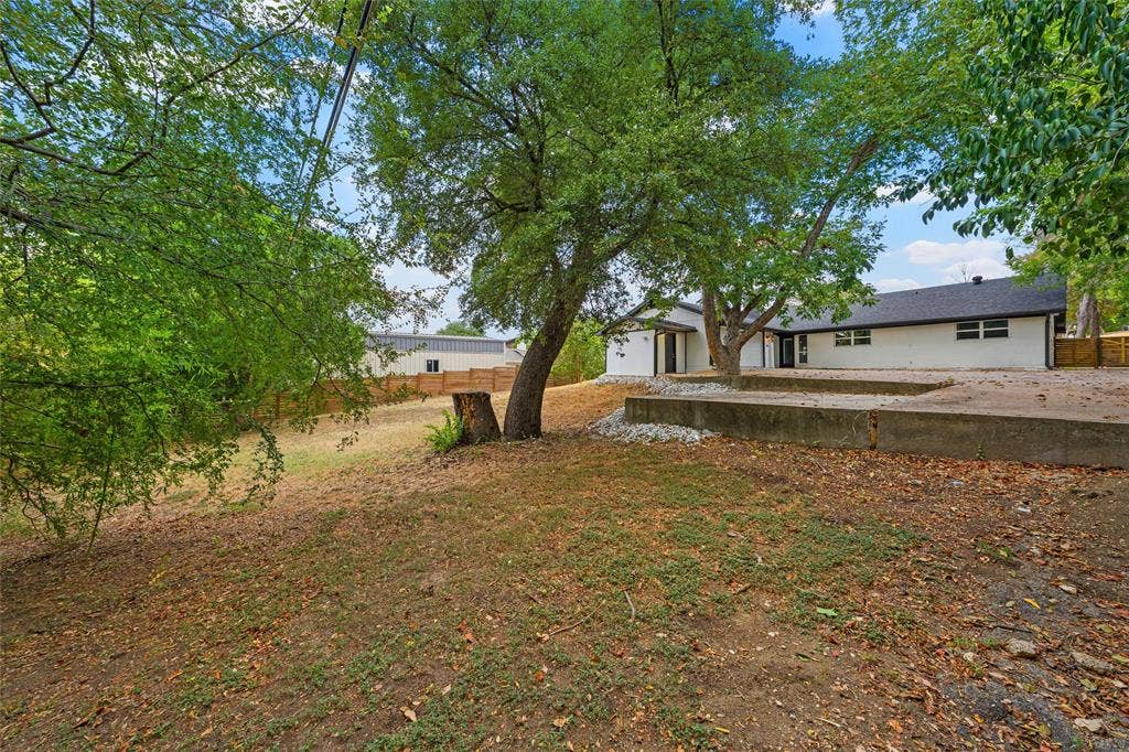 1132 Western Oaks Drive, Woodway, TX 76712 Expansive backyard featuring mature trees, a concrete patio, and a sloped terrain