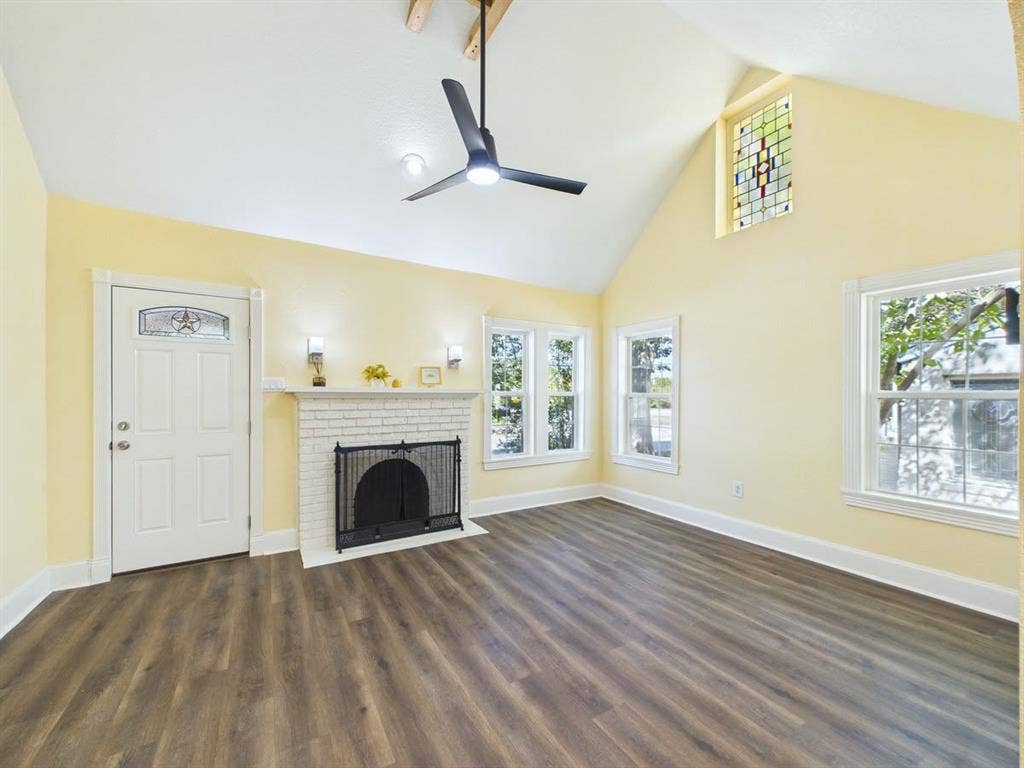 510 S Westmoreland Road, Dallas, TX 75211 Spacious interior featuring a vaulted ceiling, wood-finish flooring, white brick fireplace, and multiple windows