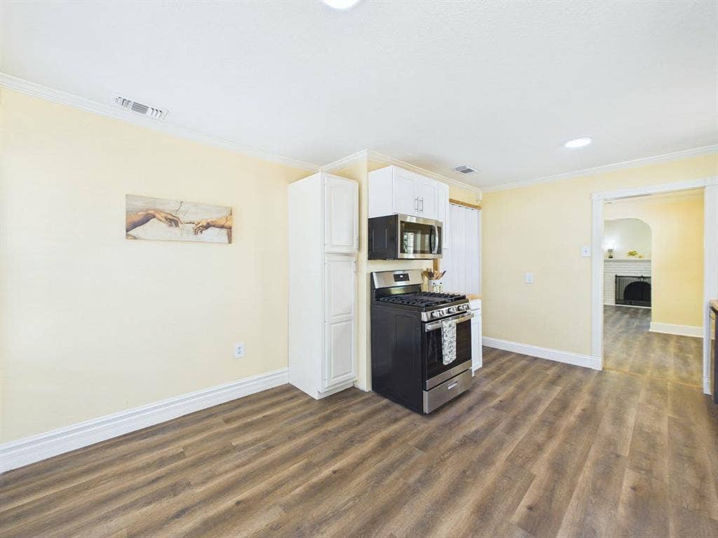 510 S Westmoreland Road, Dallas, TX 75211 Wood-finish flooring throughout, white upper and lower cabinetry, stainless steel range, and built-in microwave