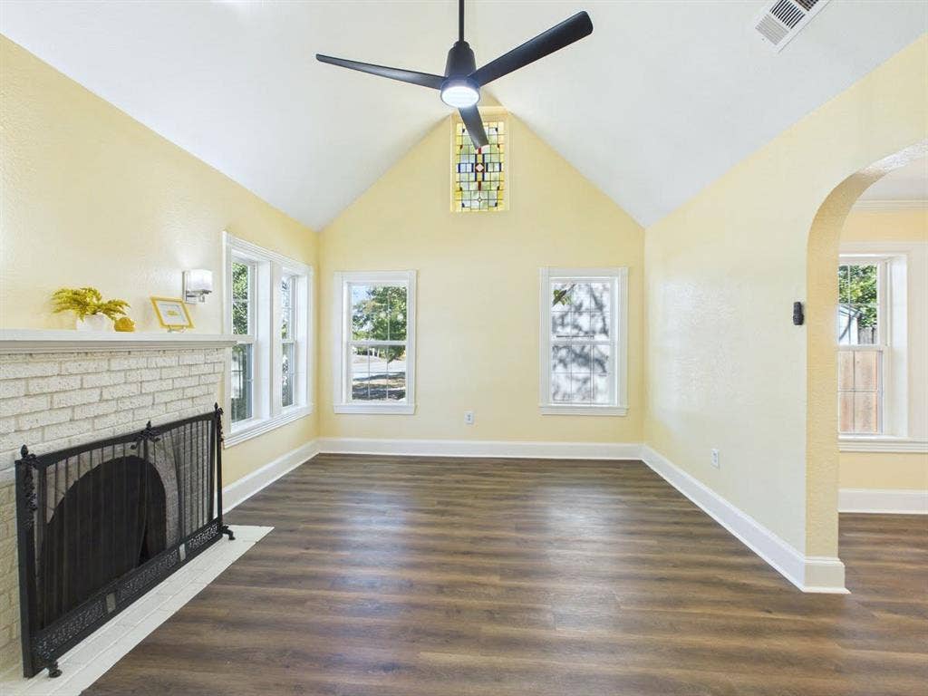 510 S Westmoreland Road, Dallas, TX 75211 Vaulted ceiling, wood-finish flooring, white brick fireplace, stained glass window, and an arched doorway