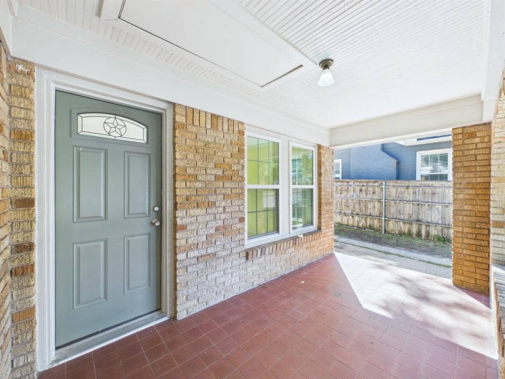 510 S Westmoreland Road, Dallas, TX 75211 Covered porch with brick siding, a paneled entry door with decorative glass insert, and a tiled floor