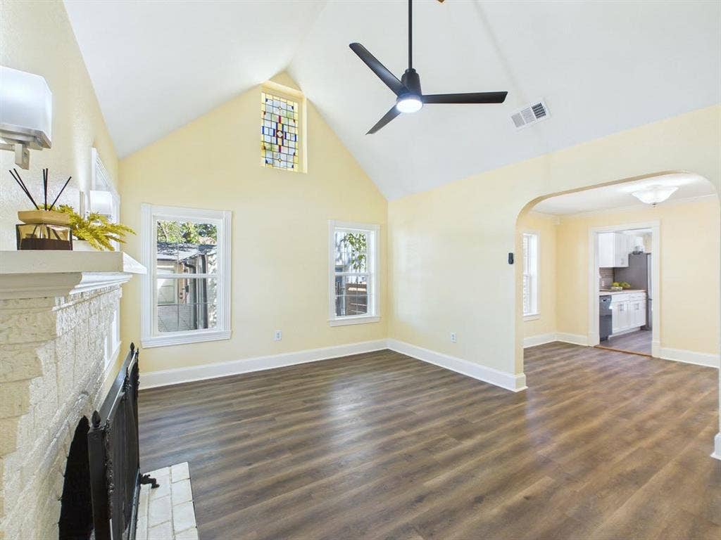 510 S Westmoreland Road, Dallas, TX 75211 Vaulted ceiling with a stained-glass window, wood-finish flooring, a painted brick fireplace, and a modern ceiling fan