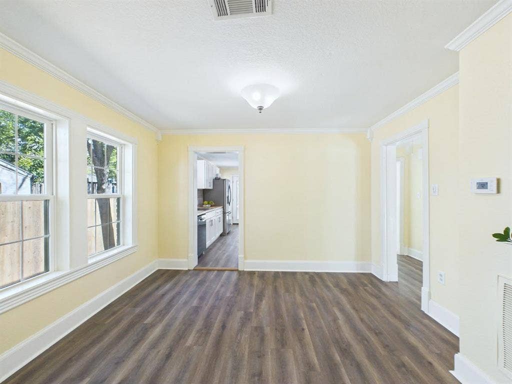 510 S Westmoreland Road, Dallas, TX 75211 Spacious room featuring wood-finish flooring, multiple windows, and crown molding