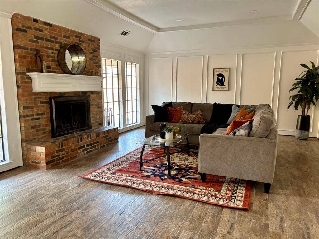 3713 San Juan Circle, Plano, TX 75023 Brick fireplace with a white mantel, wood-finish flooring, white paneling, and vaulted ceilings