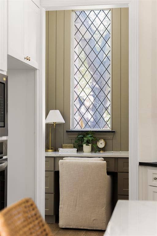 5901 Glen Heather Drive, Plano, TX 75093 Dedicated desk nook adjacent to the kitchen combines built-in cabinetry and workspace with a striking leaded-glass window, creating a functional spot for work, organization, or household planning.