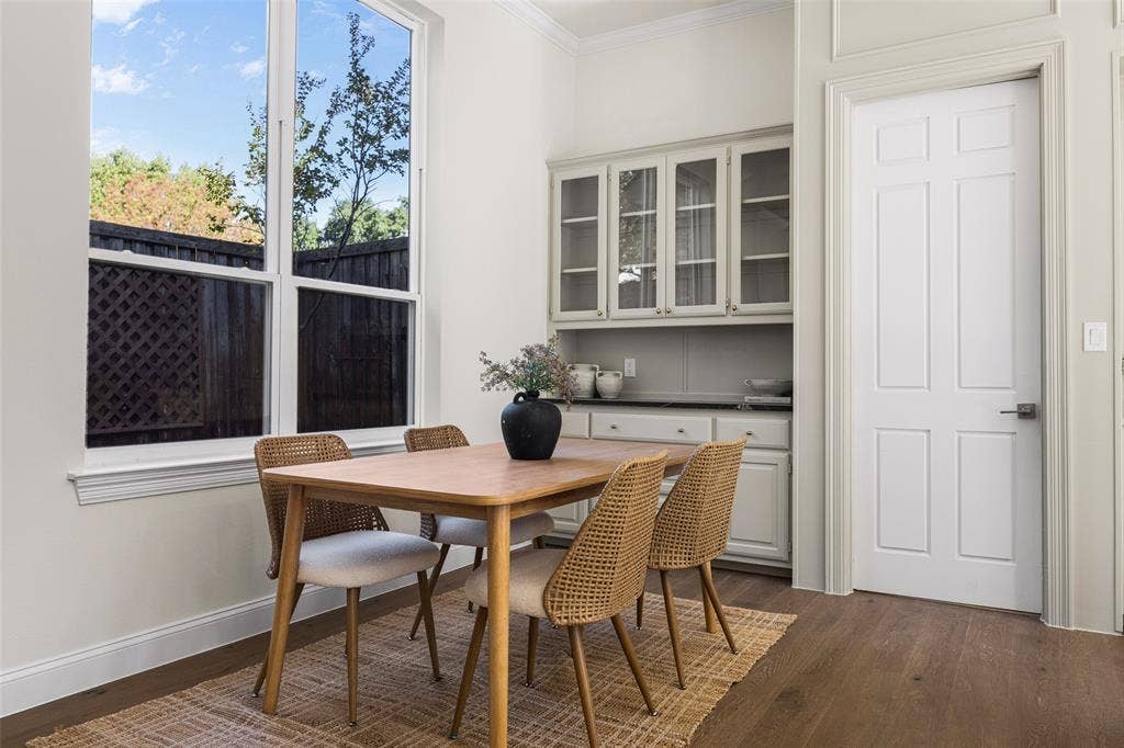 5901 Glen Heather Drive, Plano, TX 75093 Light-filled breakfast area with oversized windows, warm wood flooring, and extensive glass-front built-in cabinetry offering additional display space, storage, and serving functionality.