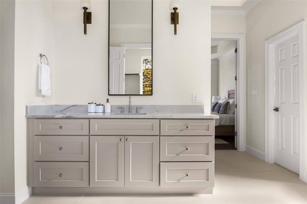 5901 Glen Heather Drive, Plano, TX 75093 Separate primary vanity offers generous counter and storage space, tailored cabinetry, a tall framed mirror, contemporary sconces, and soft neutral finishes.