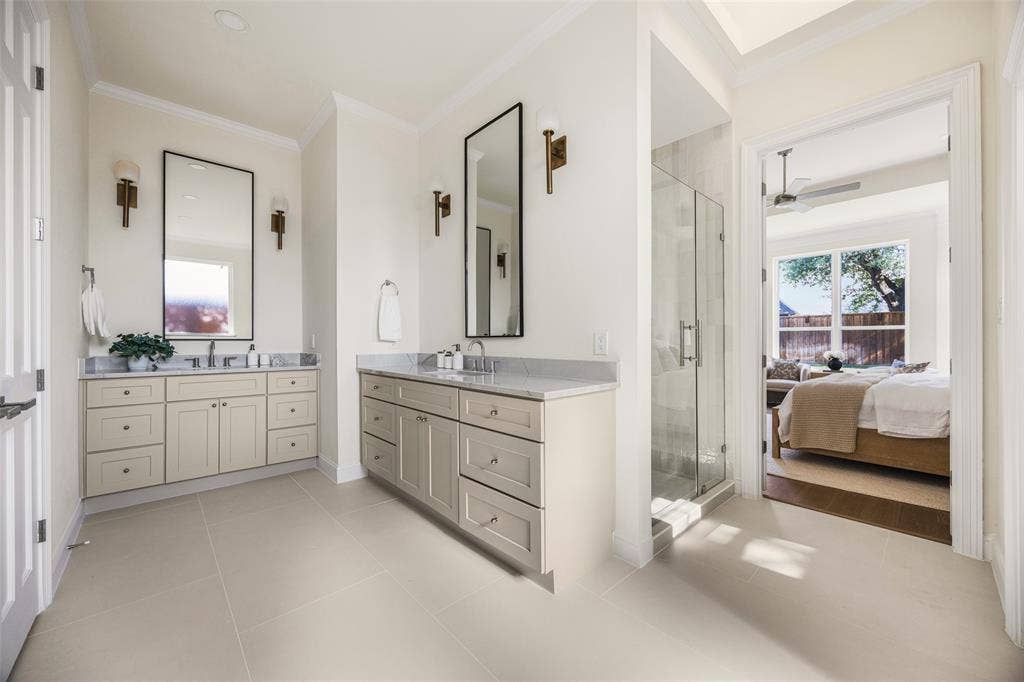 5901 Glen Heather Drive, Plano, TX 75093 Spacious en-suite bath with separate vanities, tall framed mirrors, designer sconces, a glass-enclosed shower, abundant cabinetry, and direct connection to the primary bedroom.