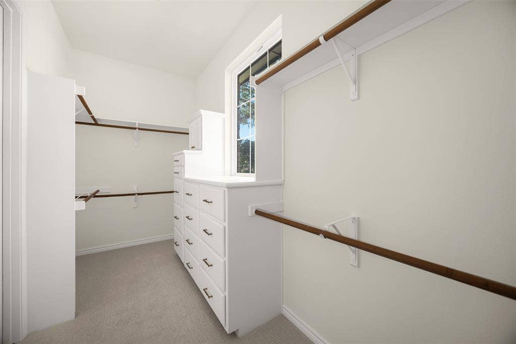 5901 Glen Heather Drive, Plano, TX 75093 Substantial primary walk-in closet provides extensive hanging space, multiple built-in drawer banks, shelving, and a window introducing valuable natural light.