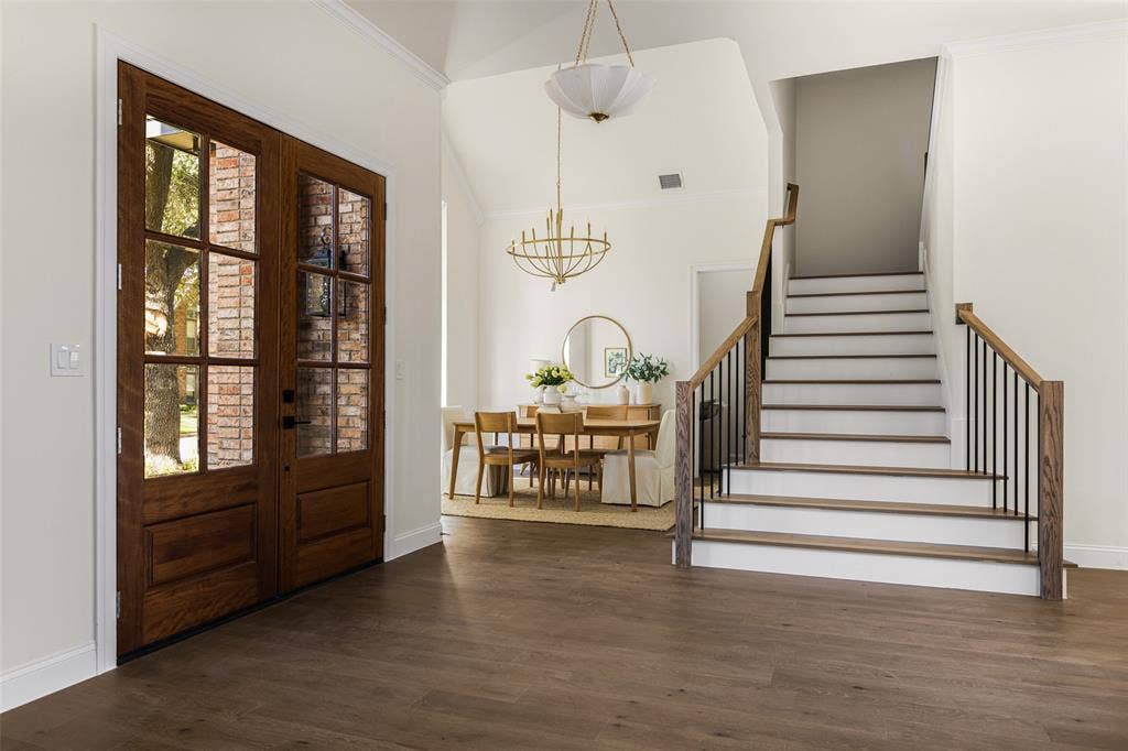 5901 Glen Heather Drive, Plano, TX 75093 Welcoming two-story entry showcases updated double wood-and-glass doors, wide-plank flooring, a redesigned staircase with wood handrails and black iron balusters, and an open connection to the formal dining room.