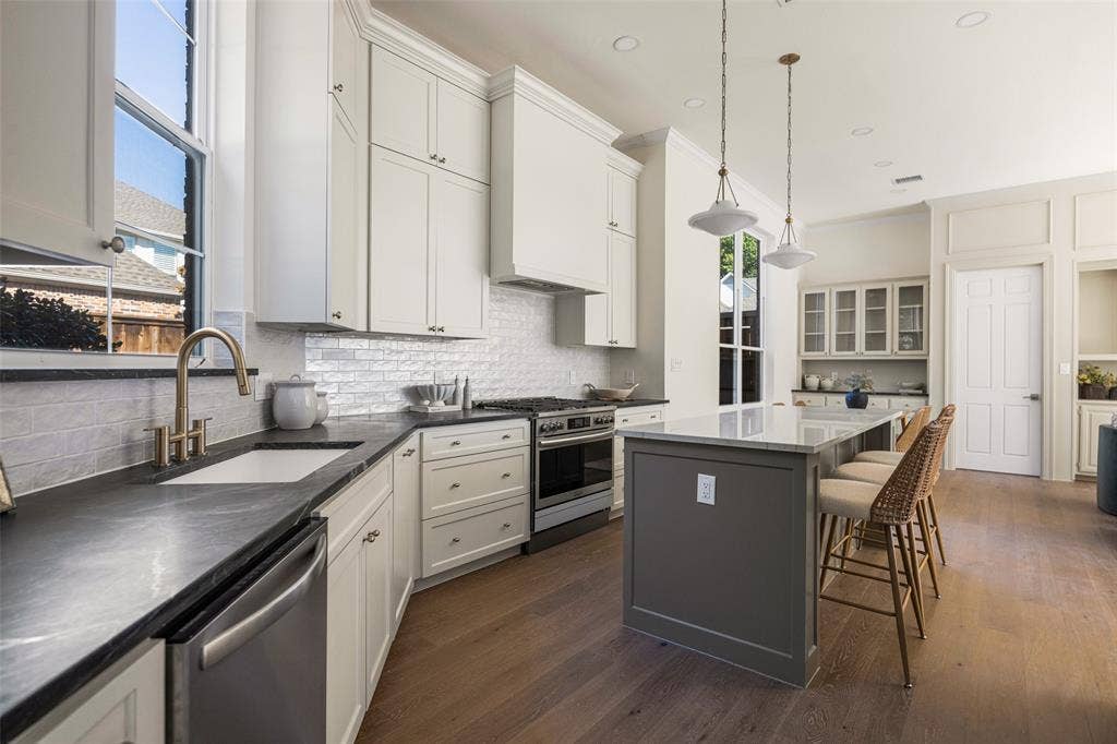 5901 Glen Heather Drive, Plano, TX 75093 Oversized island with seating, two-tone cabinetry, extensive storage, gas cooking, pendant lighting, and generous workspace for both everyday use and entertaining make this kitchen both fabulous and functional.