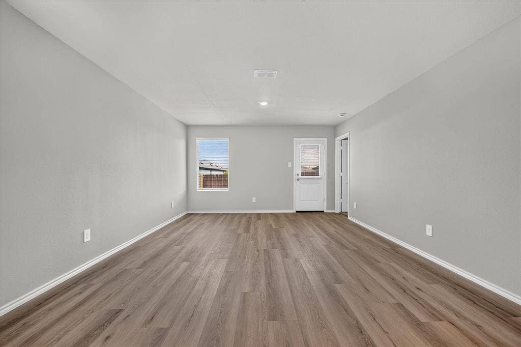 5413 Flannel Lane, Denton, TX 76249 Spacious room featuring wood-finish flooring, neutral-toned walls, and a white exterior door with an inset window