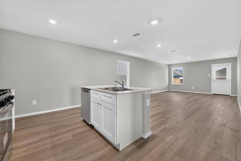 5413 Flannel Lane, Denton, TX 76249 Open-concept living area featuring wood-finish flooring, recessed lighting, and a kitchen island with a double basin sink