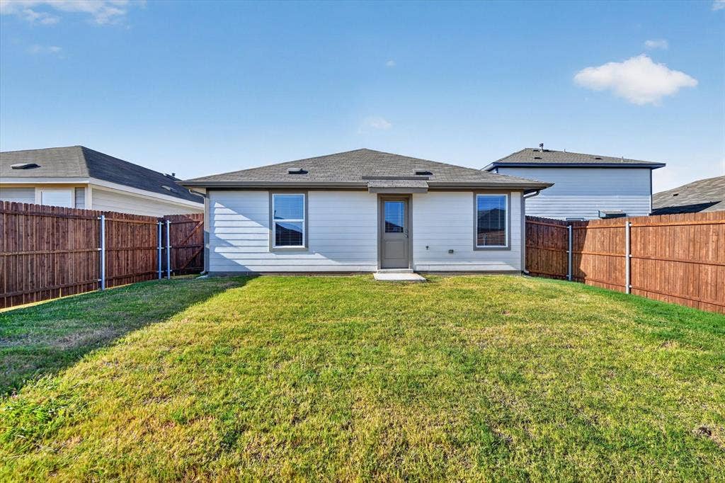 5413 Flannel Lane, Denton, TX 76249 Expansive backyard featuring a manicured lawn, a full wood fence, and a neutral-toned siding exterior