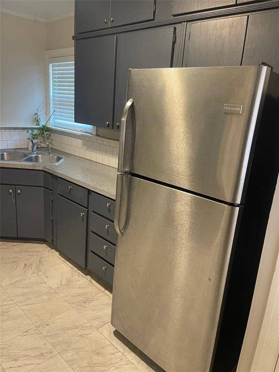 1527 Harbor Road, #1527, Dallas, TX 75216 Kitchen featuring dark cabinetry, light-toned countertops, a stainless steel refrigerator, a double basin sink, and a tile backsplash