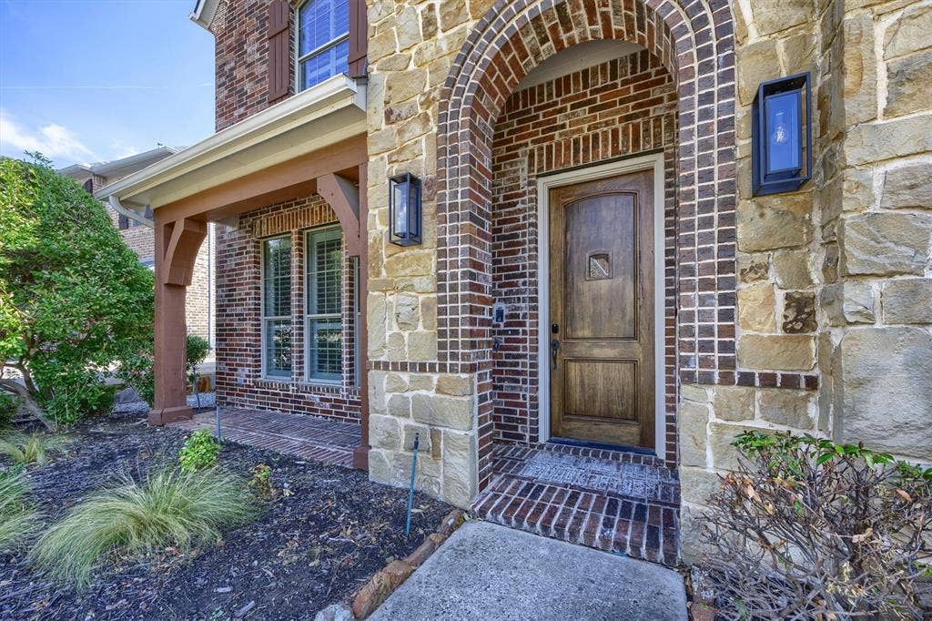 5960 Indigo Sky Drive, Frisco, TX 75036 Stone and brick are mixed with a patio on the front of the home.