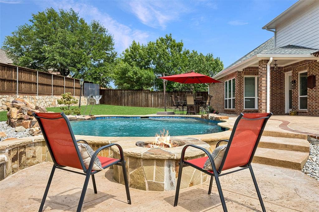 1011 Three Rivers Drive, Prosper, TX 75078 Resort-style backyard oasis featuring a sparklingpool, fire pit seating area, expansive patio, and generous green space for entertaining and play.