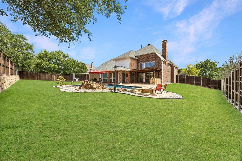 1011 Three Rivers Drive, Prosper, TX 75078 Expansive backyard with a sparkling pool, fire pit,pergola-covered patio, and generous grassy play space, creating the ultimate setting for outdoor living and entertaining.