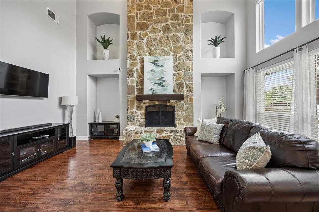 1011 Three Rivers Drive, Prosper, TX 75078 Soaring ceilings and a dramatic floor-to-ceilingstone fireplace create a stunning focal point in this light-filled living room, complete with rich wood floors and oversized windows.