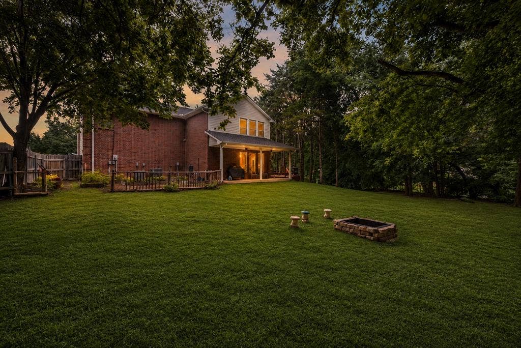 7030 Pecan Creek Circle, Midlothian, TX 76065 Spacious, tree-lined backyard with a covered patio, expansive lawn, and fire pit—perfect for relaxing, entertaining, or enjoying the outdoors.
