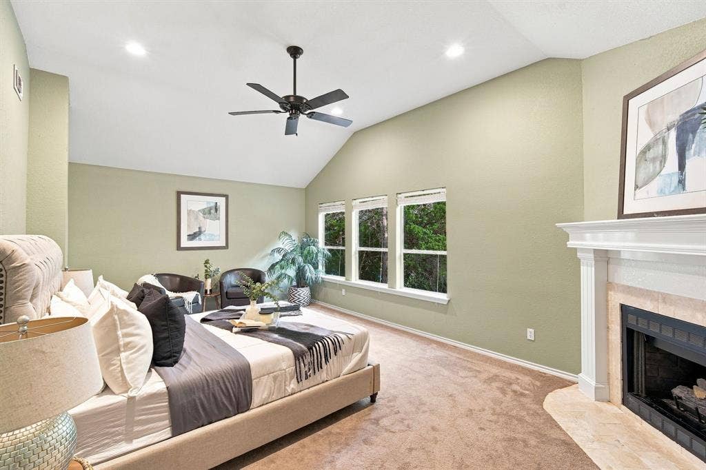 7030 Pecan Creek Circle, Midlothian, TX 76065 Inviting space with vaulted ceilings, oversized windows, and a cozy fireplace framed in natural stone, full of light and warmth.
