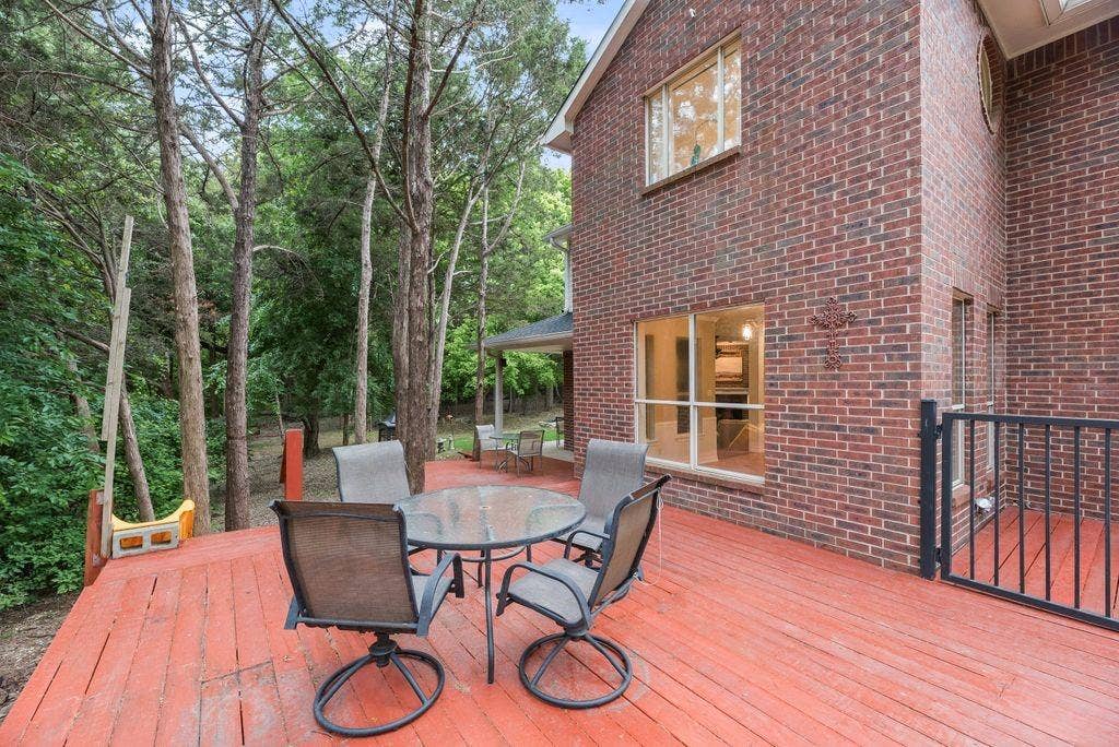 7030 Pecan Creek Circle, Midlothian, TX 76065 Spacious backyard deck surrounded by mature trees offers a peaceful, private setting perfect for outdoor dining, entertaining, or simply relaxing at home.