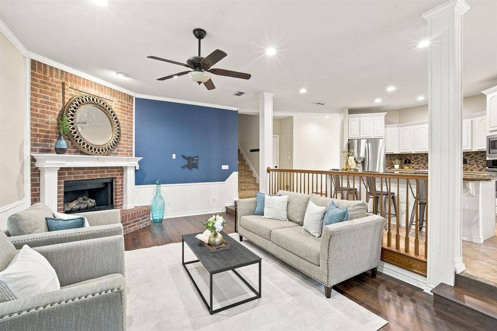7030 Pecan Creek Circle, Midlothian, TX 76065 Sun-filled living area with gleaming floors, recessed lighting, a cozy brick fireplace, and an easy flow into the open white kitchen.