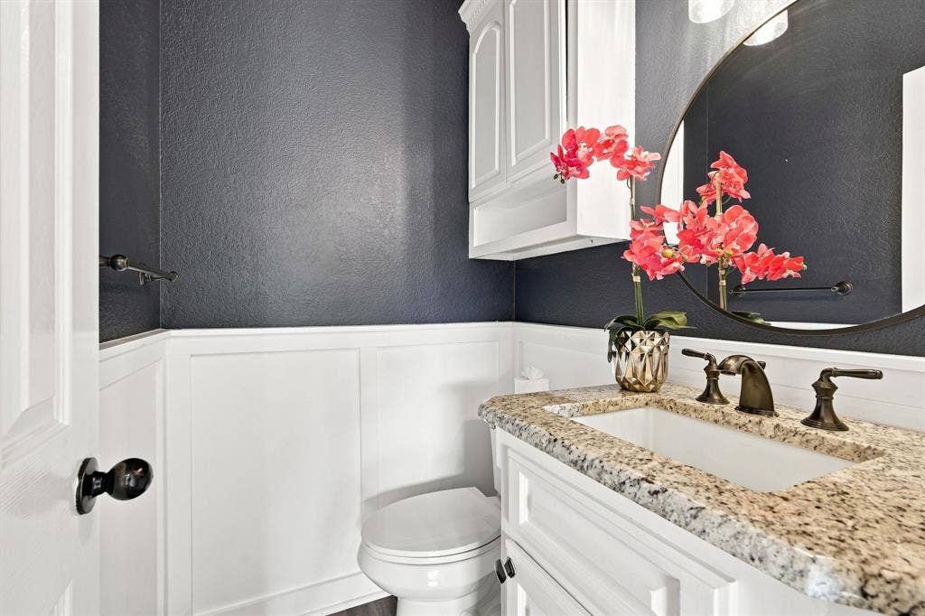 7030 Pecan Creek Circle, Midlothian, TX 76065 Stylish powder bath accented with white wainscoting and a bold dark wall color.