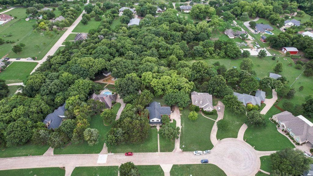 7030 Pecan Creek Circle, Midlothian, TX 76065 Aerial view highlights the home’s beautiful setting, mature trees, spacious lot, and peaceful neighborhood surroundings