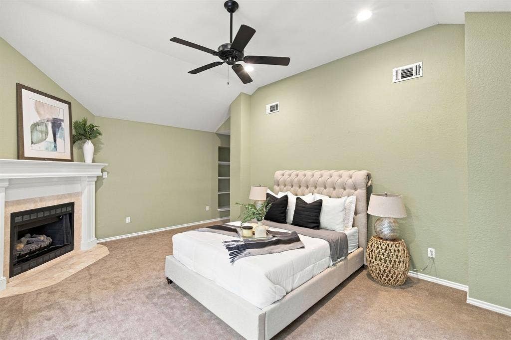 7030 Pecan Creek Circle, Midlothian, TX 76065 Spacious primary room with vaulted ceilings and a charming corner fireplace with a white mantel and tile surround.