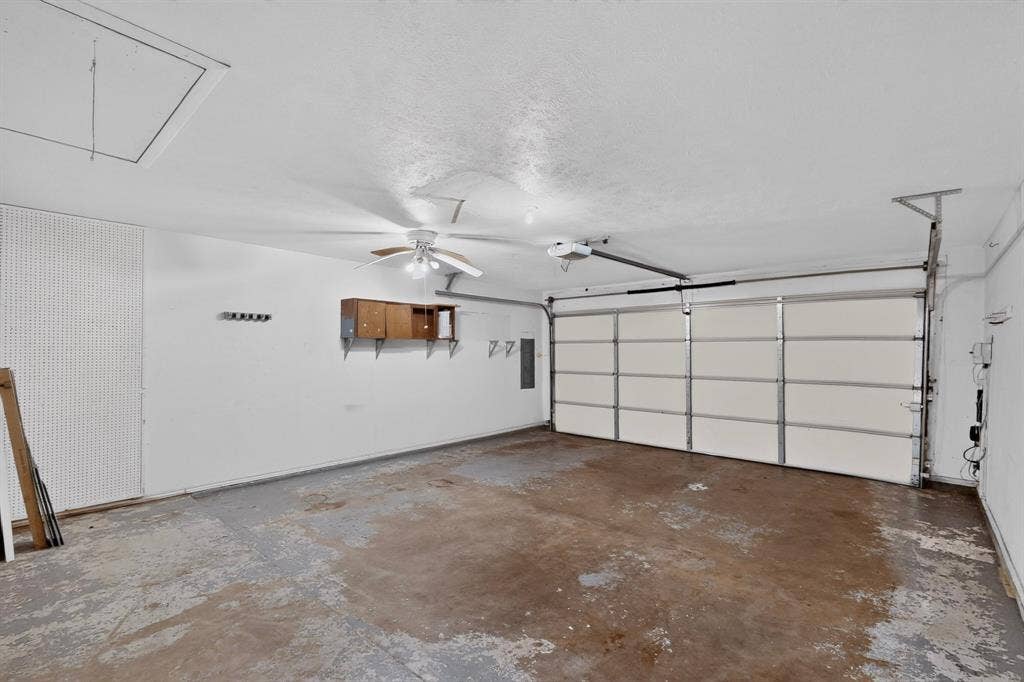 1606 Treehouse Lane, Plano, TX 75023 Single-bay garage with an overhead door, built-in shelving, and a ceiling fan