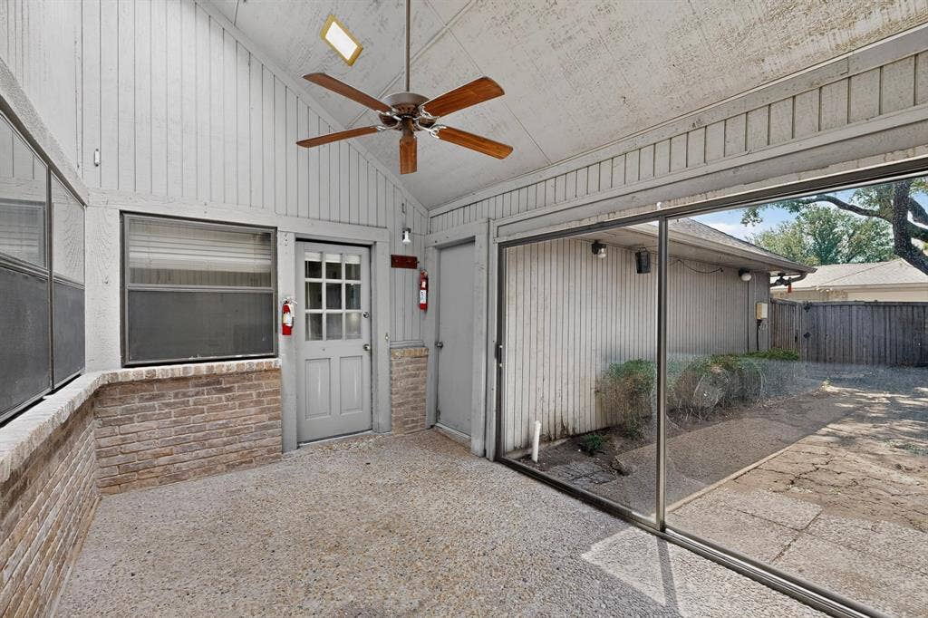 1606 Treehouse Lane, Plano, TX 75023 Enclosed patio featuring a vaulted ceiling, exposed aggregate flooring, brick wainscoting, and a ceiling fan with light