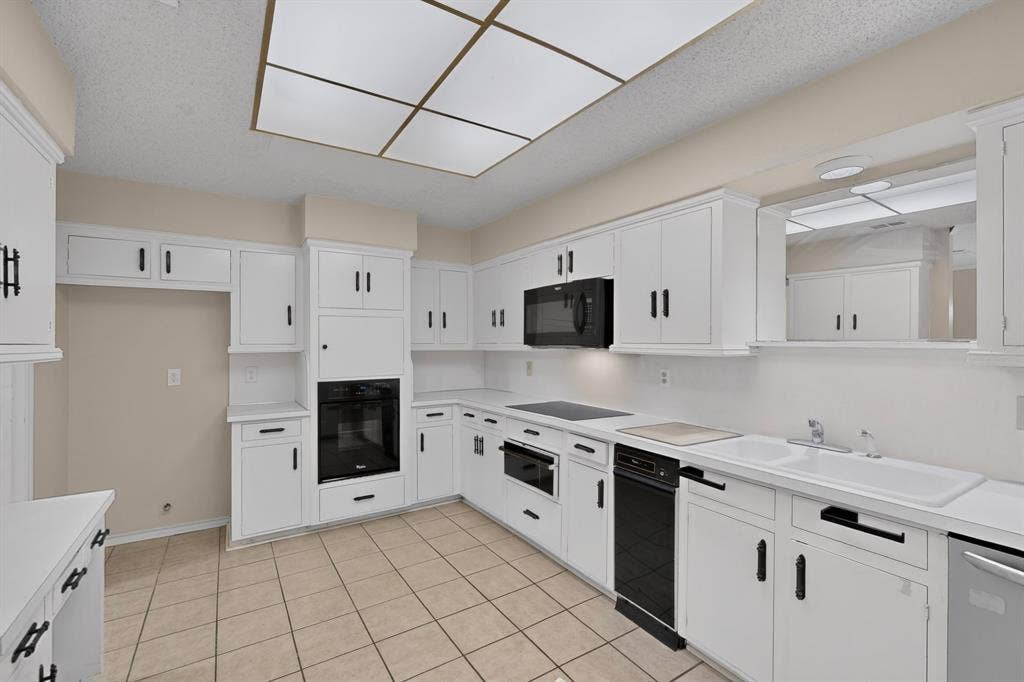 1606 Treehouse Lane, Plano, TX 75023 Kitchen featuring white cabinetry, black hardware, built-in appliances, ceramic tile flooring, and a drop-in sink