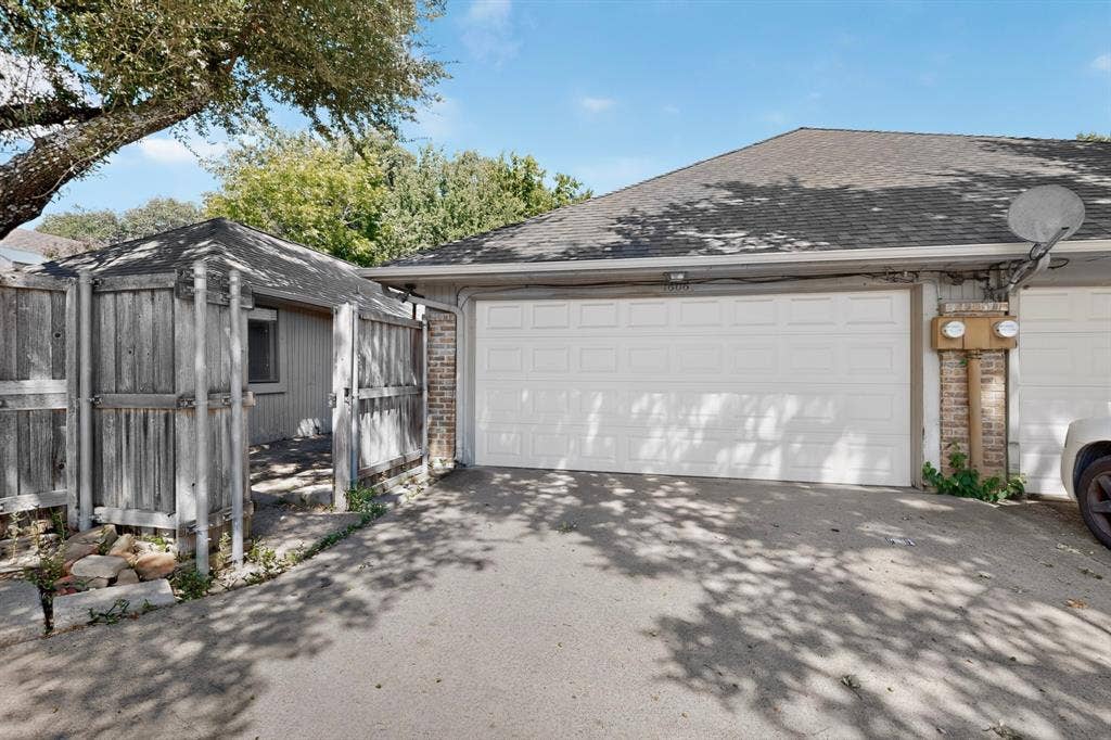 1606 Treehouse Lane, Plano, TX 75023 Asphalt driveway with an attached garage, brick detailing, and a separate fenced structure