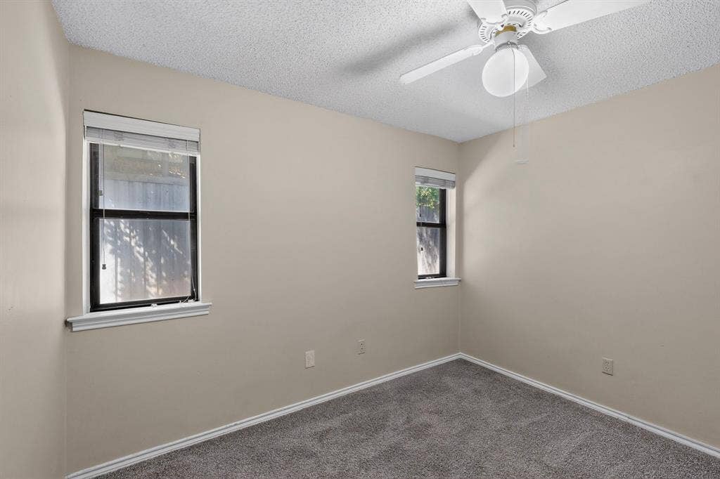 1606 Treehouse Lane, Plano, TX 75023 Textured ceiling with a ceiling fan light fixture, two windows with blinds, and gray carpeting