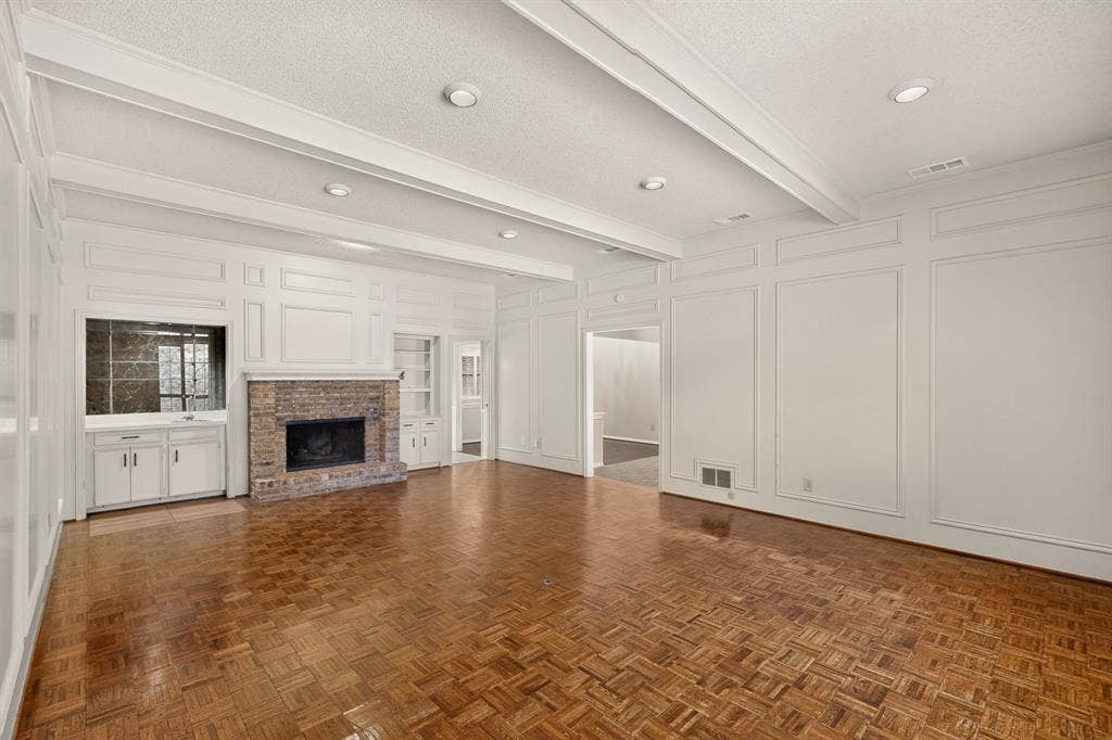 1606 Treehouse Lane, Plano, TX 75023 Wood-finish flooring, brick fireplace, built-in cabinetry, recessed lighting, and decorative wall paneling