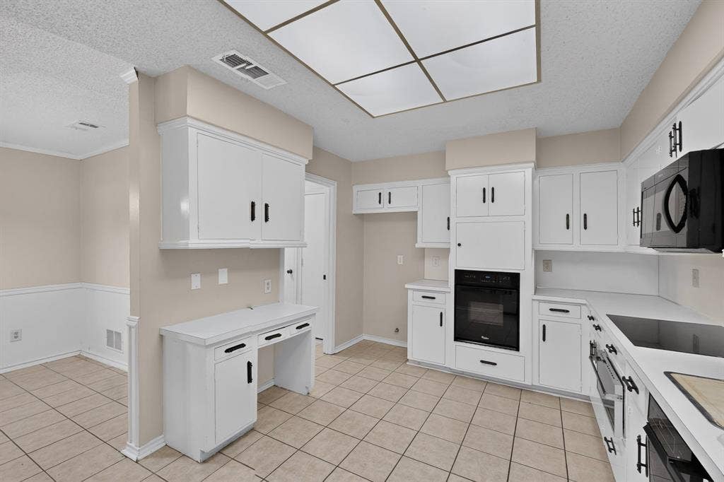 1606 Treehouse Lane, Plano, TX 75023 Kitchen featuring white cabinetry, integrated black oven, and white countertops