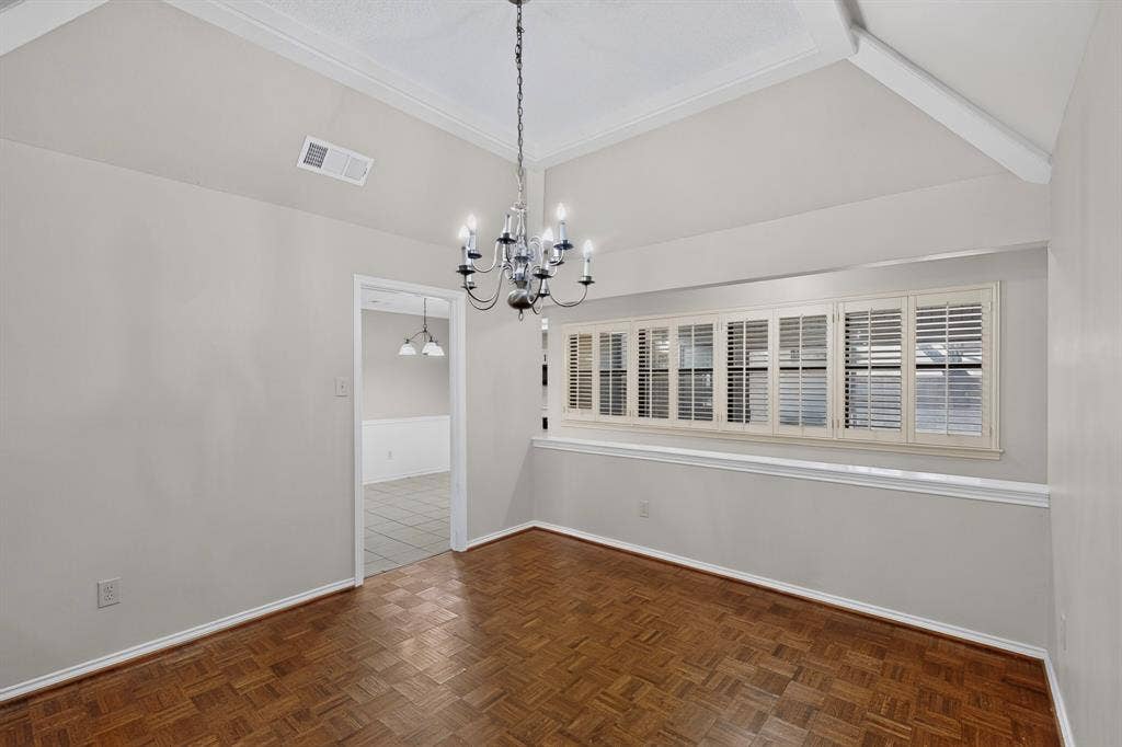 1606 Treehouse Lane, Plano, TX 75023 Elegant dining room showcasing soaring vaulted ceilings with crown molding, herringbone wood-finish flooring, and a striking multi-arm chandelier