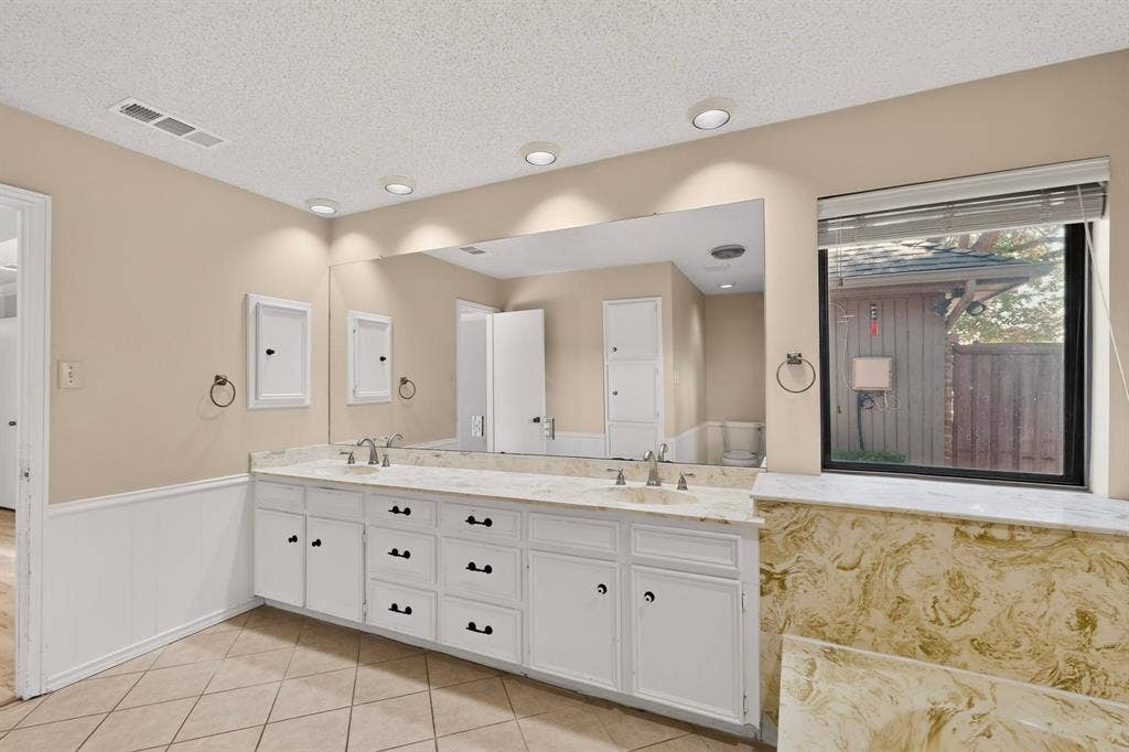 1606 Treehouse Lane, Plano, TX 75023 Dual vanity with white cabinetry, integrated sinks, an expansive mirror, and recessed lighting