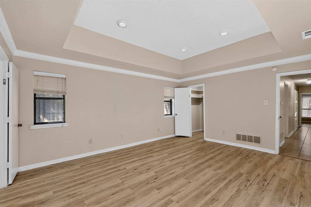 1606 Treehouse Lane, Plano, TX 75023 Recessed tray ceiling, crown molding, wood-finish flooring, two windows, and an open closet with shelving