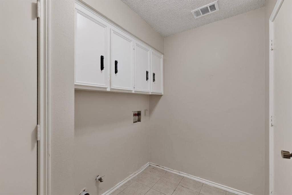 1606 Treehouse Lane, Plano, TX 75023 White cabinetry with black hardware, tile flooring, and light neutral wall paint